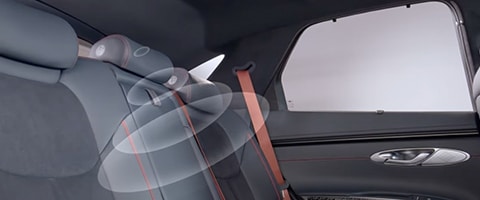 Car interior showcasing rear seat airbag deployment with red seatbelt highlighting safety features.
