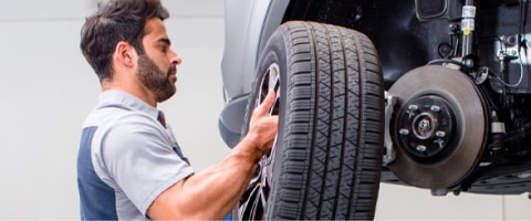 Mechanic installing a car tire in an auto repair shop, showing vehicle maintenance.