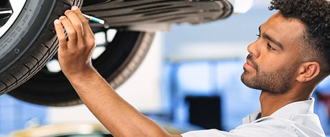 Mechanic inspecting a car tire in a garage, focusing on treads and wear.