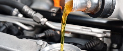 Pouring motor oil into a car engine, showcasing vehicle maintenance and lubrication.