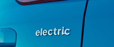 Close-up of a blue electric car with "electric" badge on the side.