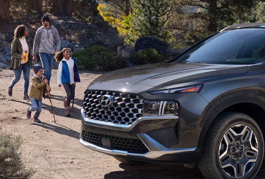 Family hiking outdoors with a Hyundai SUV in a forest setting.