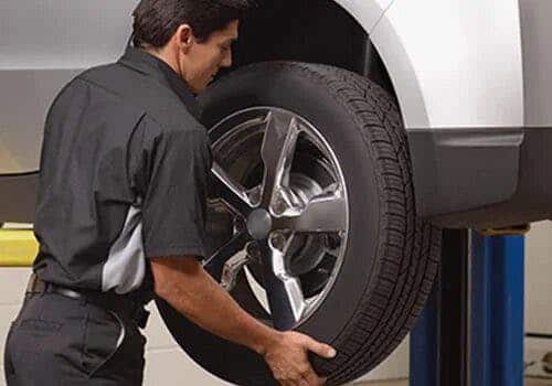 Mechanic replacing a car tire in an auto repair shop, showcasing vehicle maintenance.