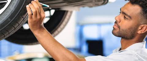 Mechanic inspecting a car tire in a garage, checking for wear and safety.