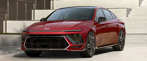 Red Hyundai sedan parked on a modern driveway, showcasing sleek design and sporty features.