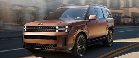 Bronze SUV with sleek design driving on a city street, highlighting its modern exterior styling.