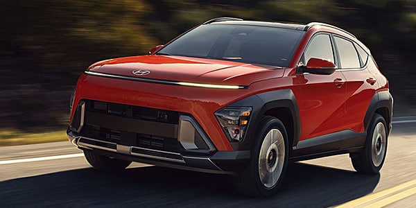 Red Hyundai SUV driving on a road, showcasing sleek design and modern features.