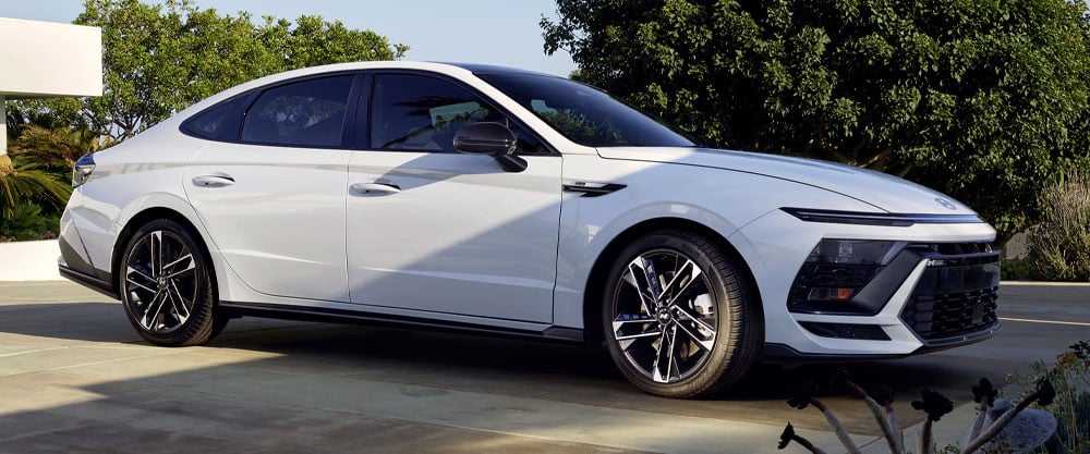Sleek white sedan parked outdoors, showcasing modern design and shiny alloy wheels.