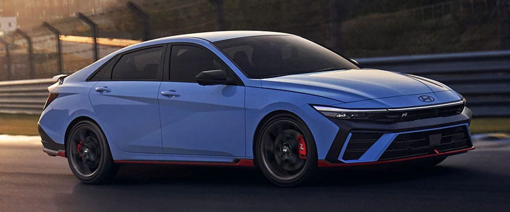 Blue sports sedan on a racetrack, showcasing sleek design and red brake calipers.