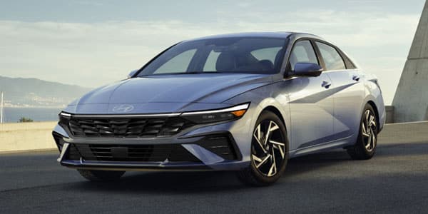 A sleek blue sedan parked on a road with mountains in the background, showcasing modern design.