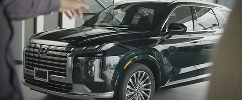 A sleek black SUV displayed in a dealership showroom with prominent grille and alloy wheels.