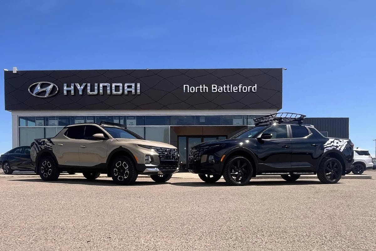 Two Hyundai trucks parked in front of a Hyundai dealership in North Battleford under a clear blue sky.