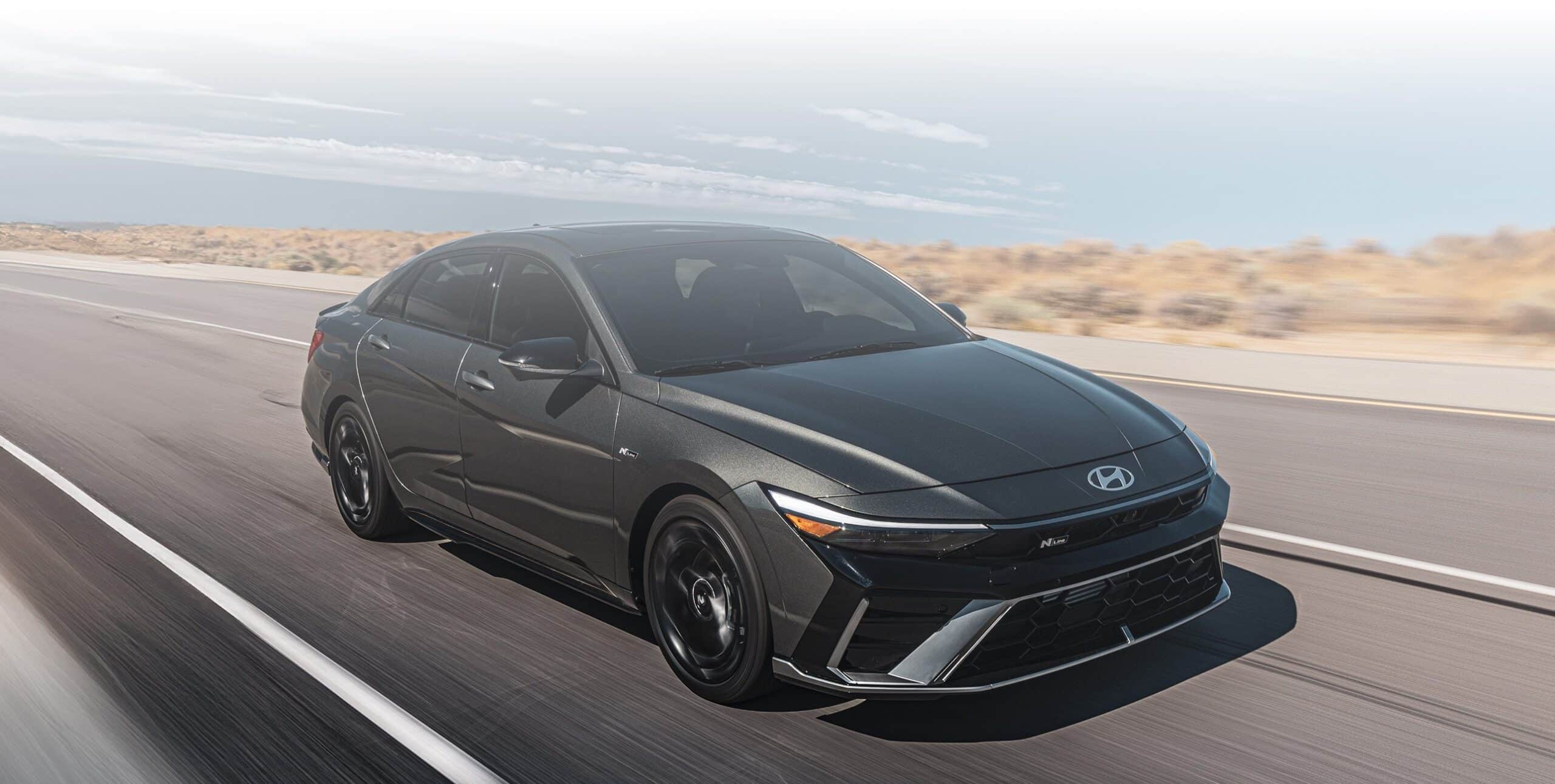Hyundai sedan driving on an open highway under a cloudy sky, showcasing sleek design.