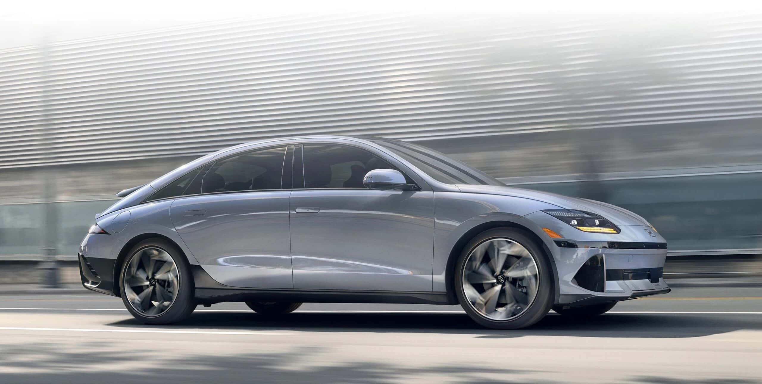 Sleek silver sedan driving on a road with a blurred background for speed effect.